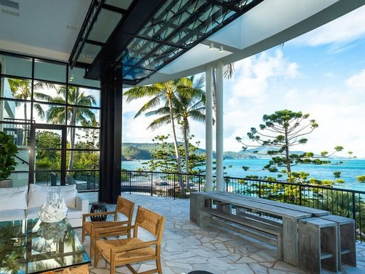A luxurious patio with a view of palm trees and the ocean