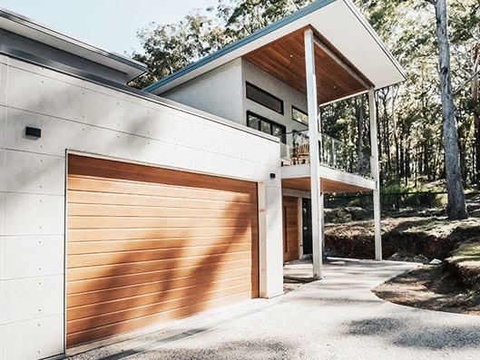 decowood garage door on a modern two story home next to woods