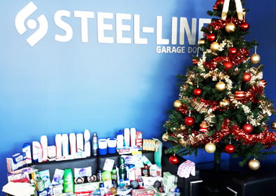 christmas tree with presents in front of steel line logo