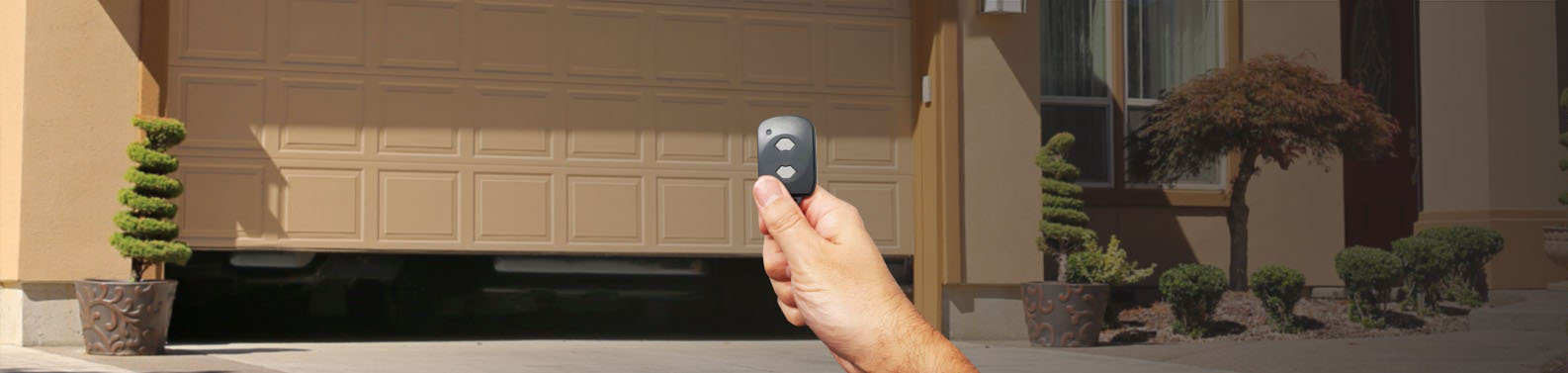 a hand using a garage door opener button to open a garage door