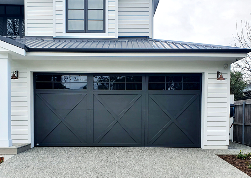 The view of a gray, modern garage door at the end of a driveway